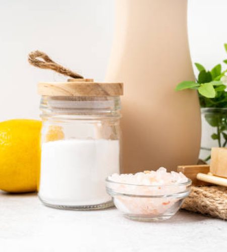 Eco friendly natural cleaners, jar with baking soda, dish brush, lemon, flowers, soap on white background. Organic ingredients for homemade cleaning with mock up bottle. Zero waste concept, copy space